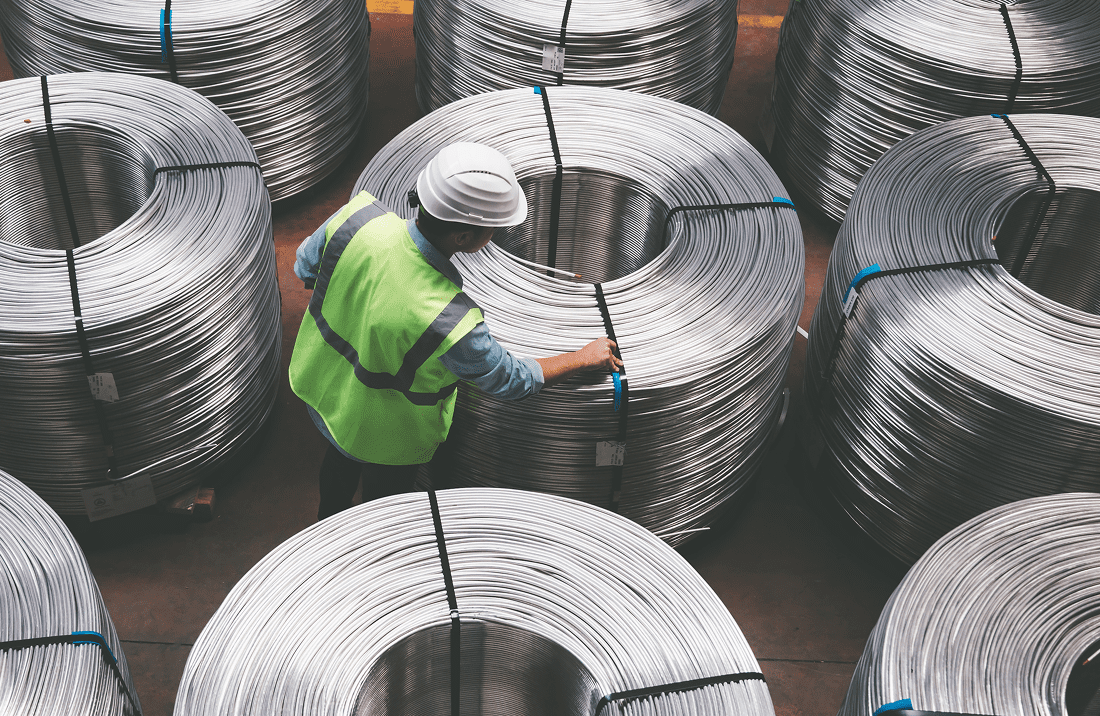 Worker inspecting large metal coils