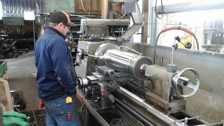 Man using metalworking lathe in workshop