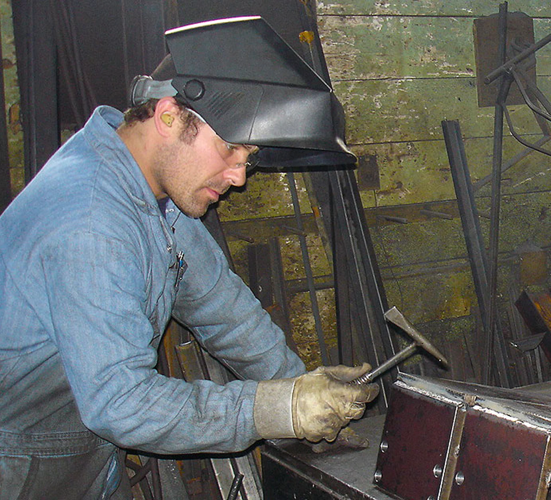 Welder working with hammer and mask